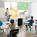 School classroom teacher teaching pupils with projector